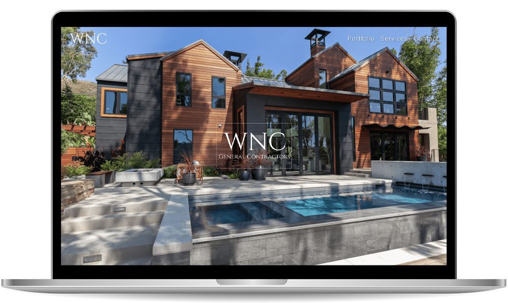 A laptop screen displaying a website for WNC General Contractors, featuring a modern house exterior with large windows, a swimming pool, and surrounding greenery.