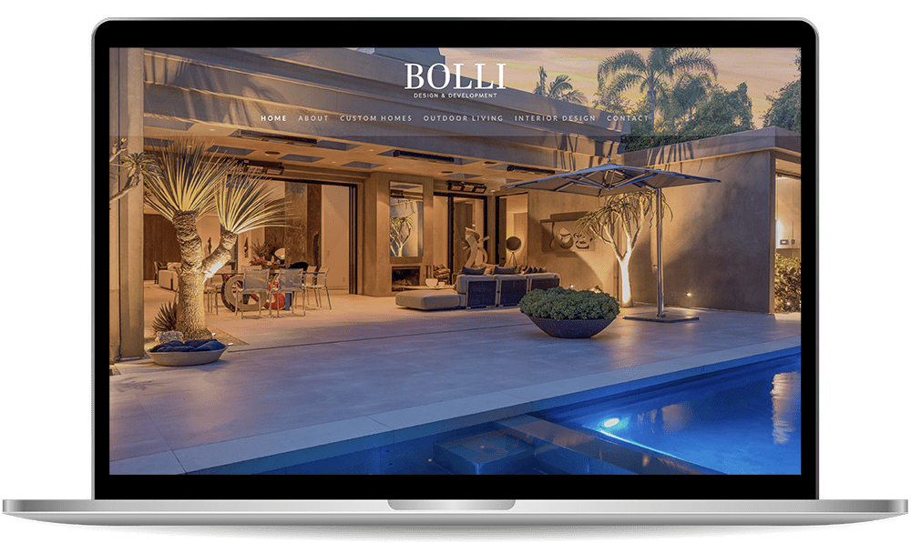 A laptop screen displays the homepage of a website for Bolli Design and Development, featuring a modern house with an outdoor living space and a pool at dusk.